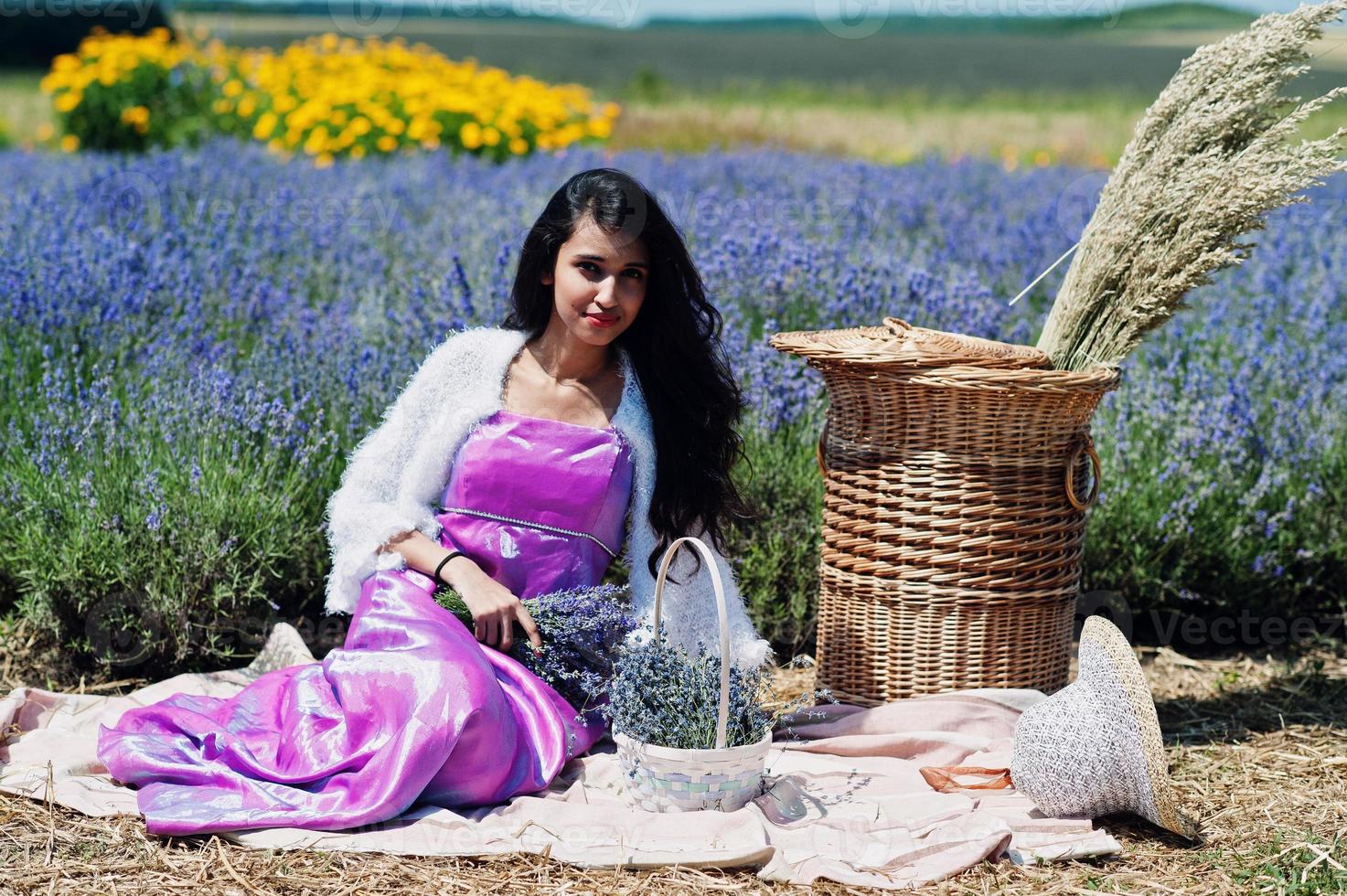 mooi indiaans meisje draagt saree india traditionele kleding in paarse lavendelveld met mand. foto