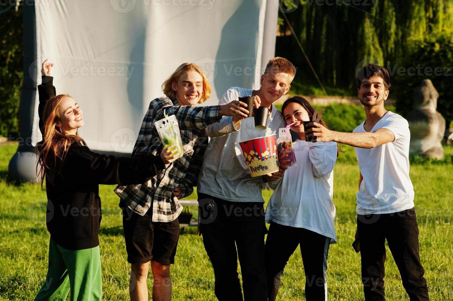 jonge multi-etnische groep mensen kijken naar film op poef in openluchtbioscoop. foto