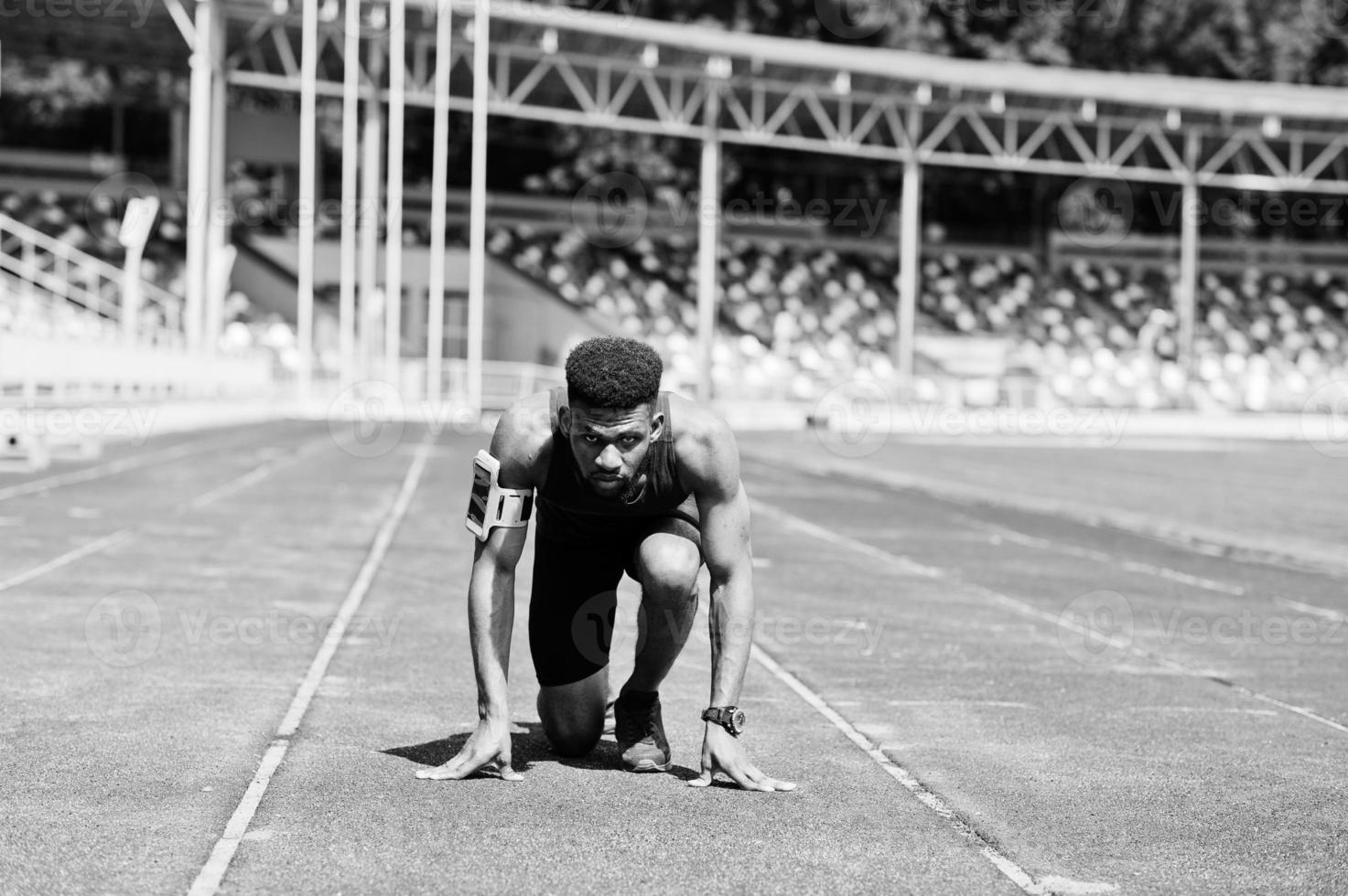 Afro-Amerikaanse mannelijke atleet in sportkleding racen alleen op een atletiekbaan in het stadion. foto