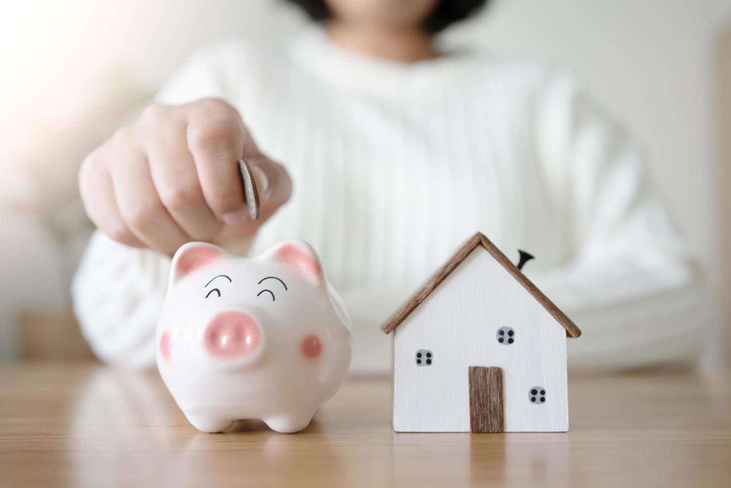 vrouw met spaarvarken en toekomstig huisconcept sparen en leengeld voor huis. om een nieuw huis te huren of te kopen met geld besparen in de spaarpot. foto