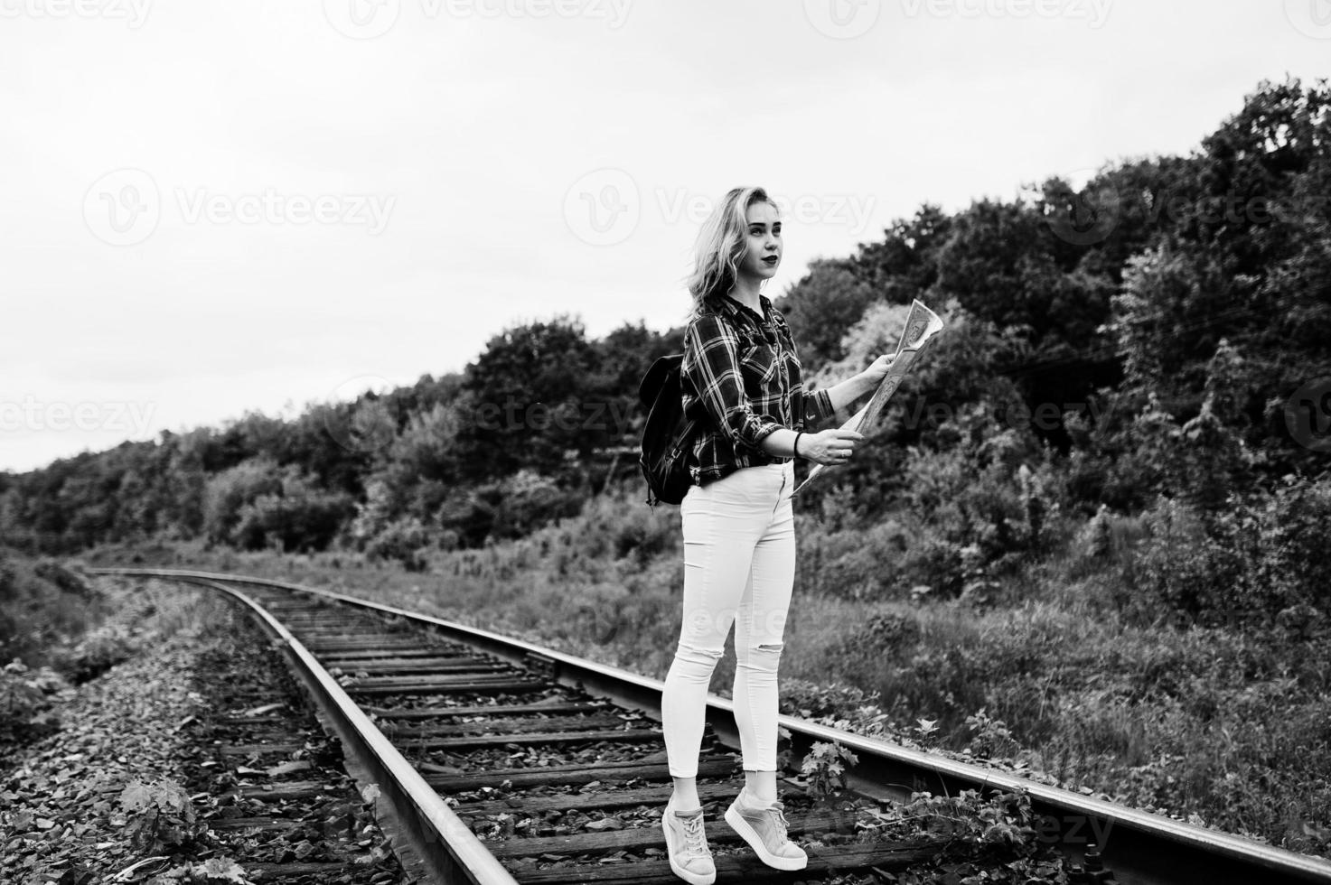 portret van een mooi blond meisje in tartan shirt wandelen op de spoorlijn met kaart in haar handen. foto