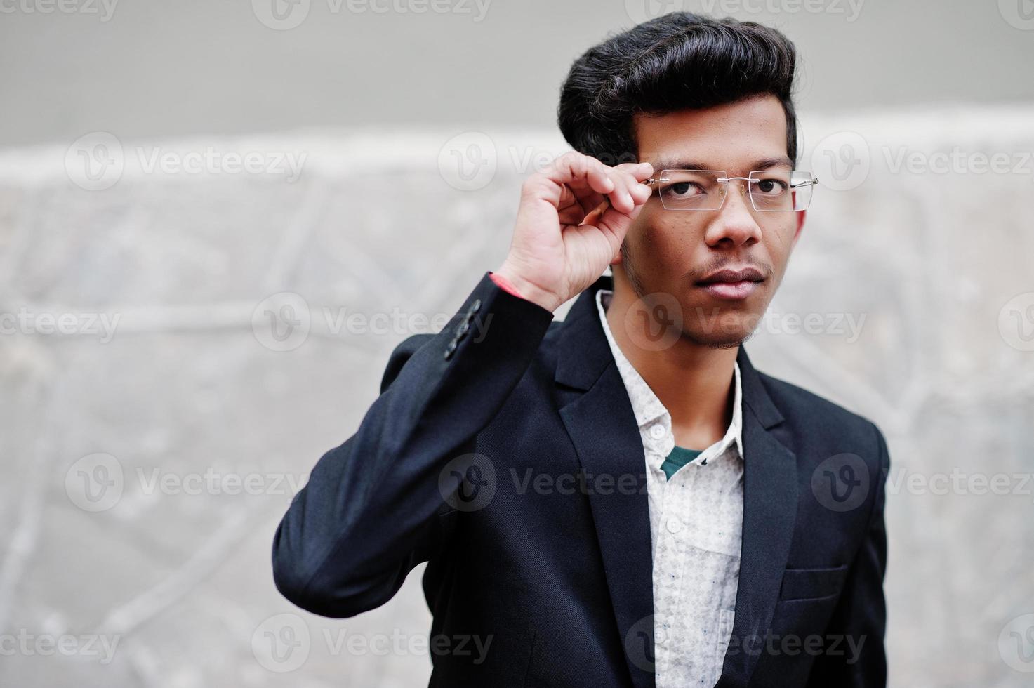 jonge Indiase man op pak en bril poseerde buiten. foto