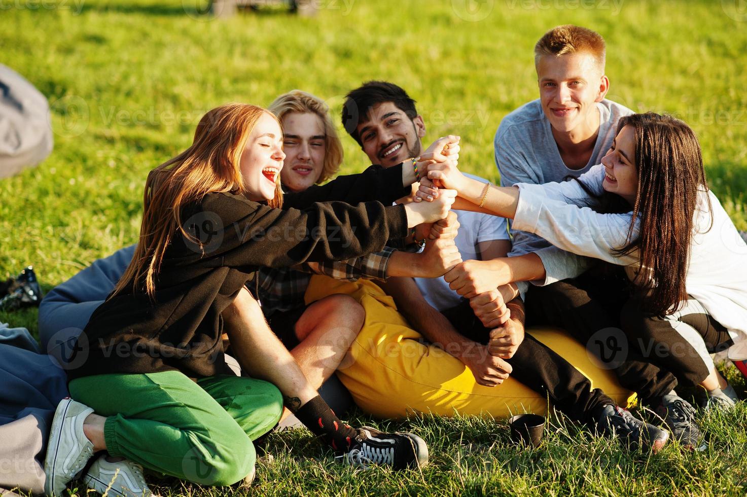 jonge multi-etnische groep mensen kijken naar film op poef in openluchtbioscoop. foto