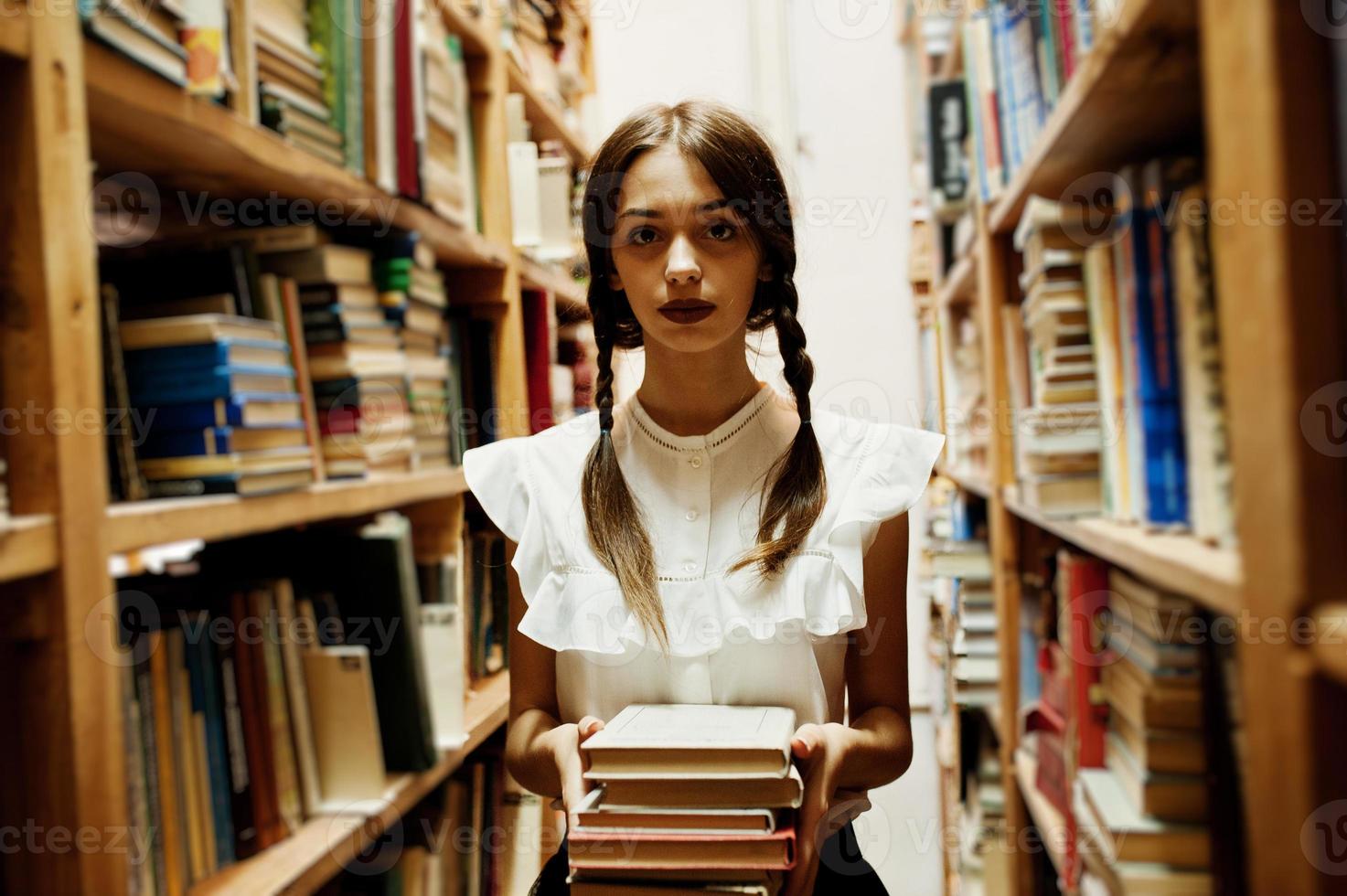 meisje met staartjes in witte blouse bij oude bibliotheek. foto