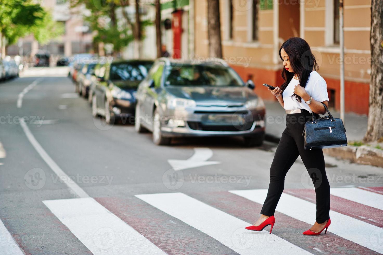 stijlvolle Afro-Amerikaanse zakenvrouw op straten van de stad op zebrapad. foto