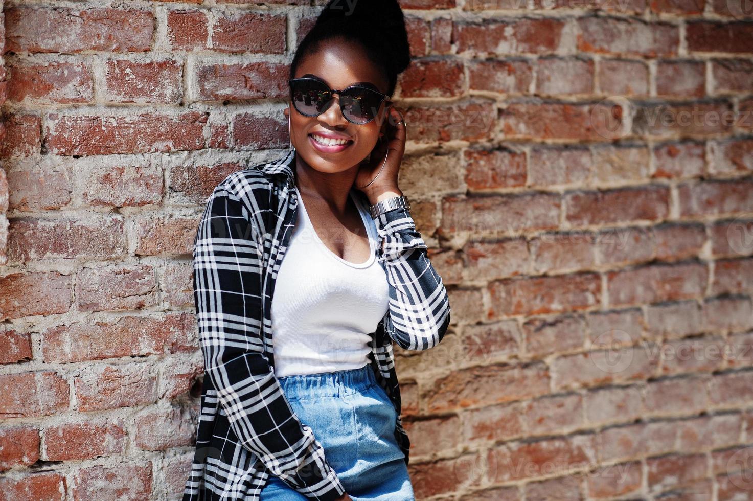hiphop afrikaans amerikaans meisje op zonnebrillen en jeansborrels. casual straatmode portret van zwarte vrouw. foto