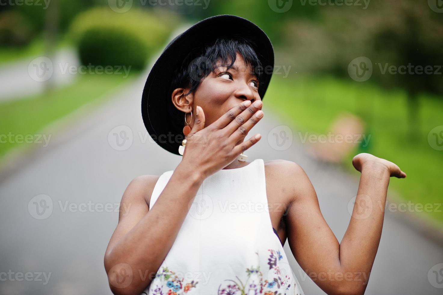 geweldige Afro-Amerikaanse modelvrouw in groene broek en zwarte hoed poseerde met verschillende emoties in het park, toont een verrassingsgezicht. foto