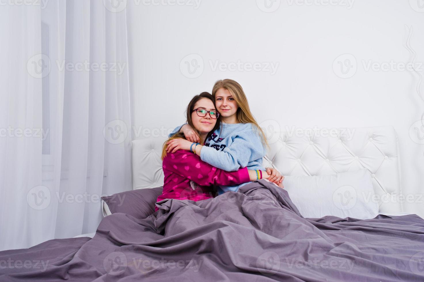 twee vrienden meisjes in pyjama plezier op bed op kamer. foto