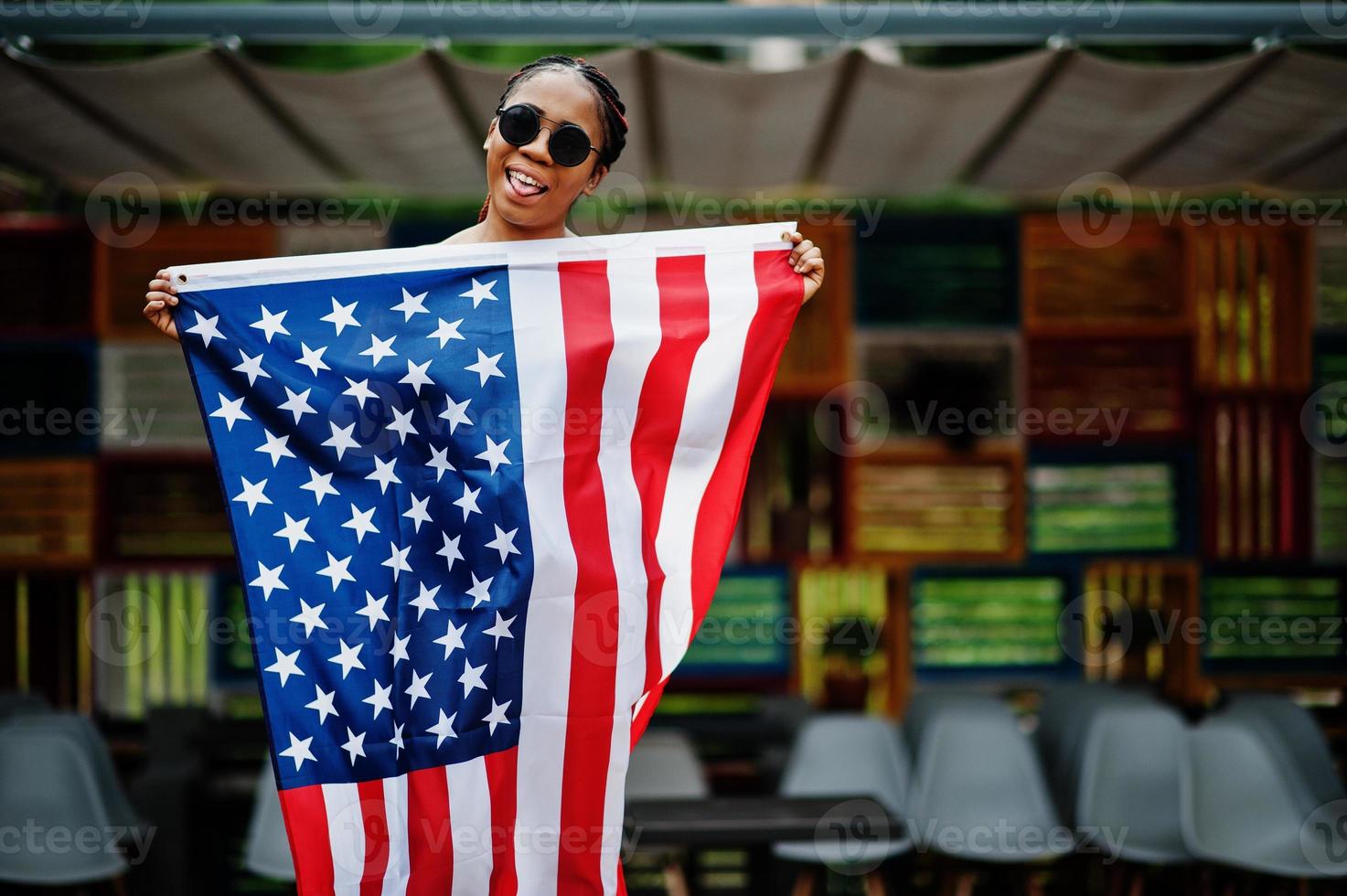 stijlvolle Afro-Amerikaanse vrouw in zonnebril poseerde buiten met usa vlag. foto