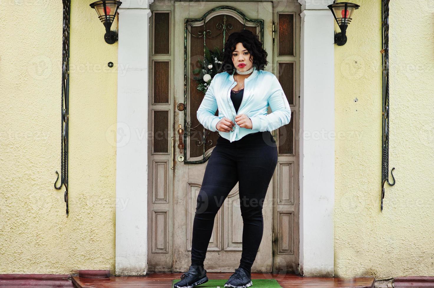 stijlvol Afrikaans-Amerikaans plus-maatmodel in de straten van de stad tegen het binnenkomen van het huis. foto