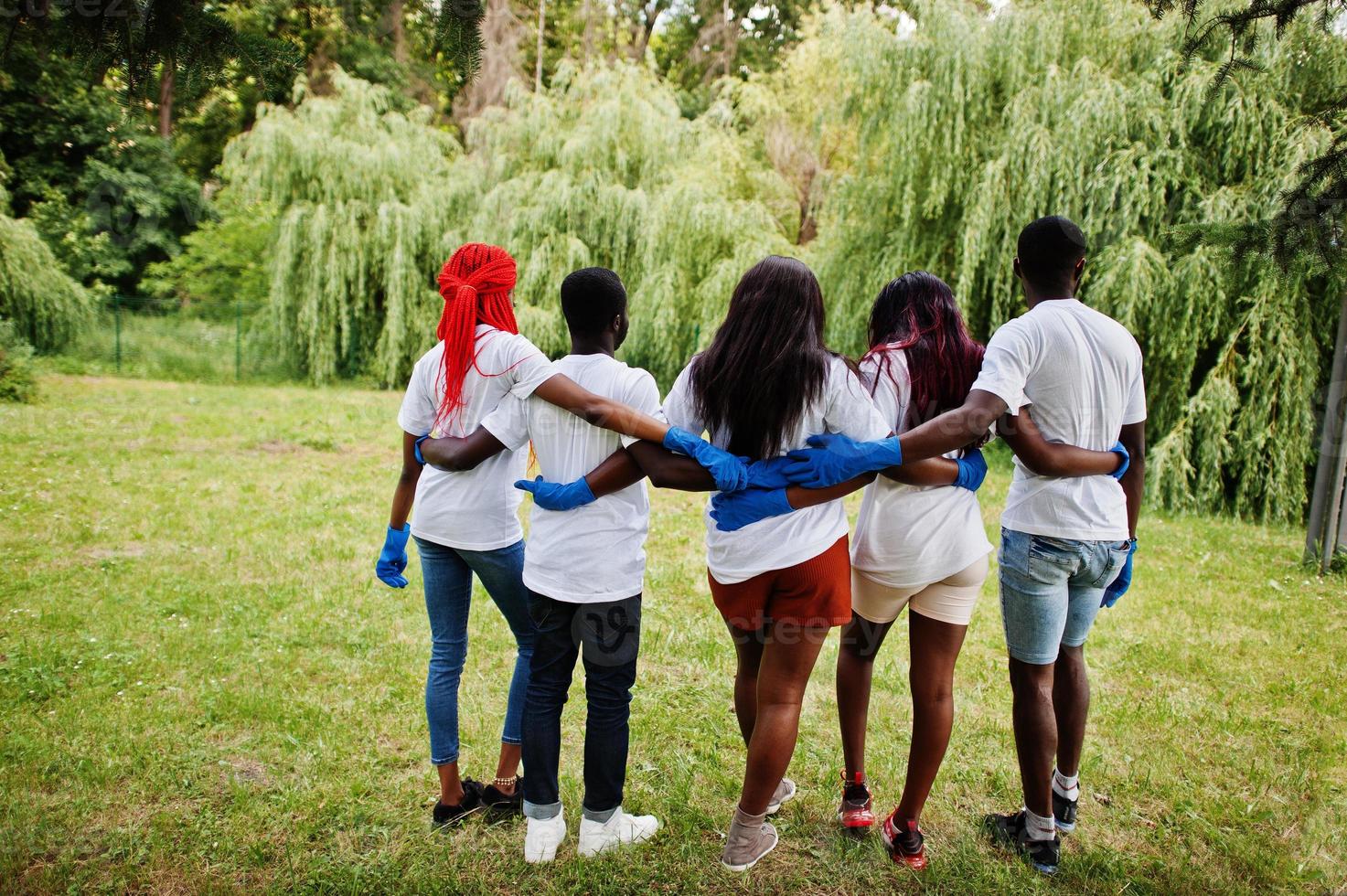 achterkant groep gelukkige Afrikaanse vrijwilligers knuffels samen in het park. Afrika vrijwilligerswerk, liefdadigheid, mensen en ecologie concept. foto