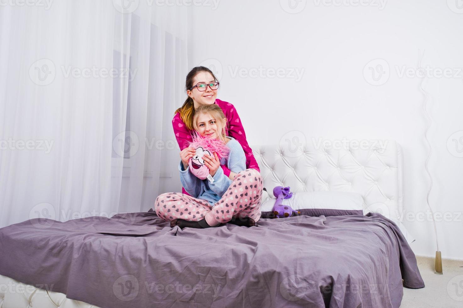 twee vrienden meisjes in pyjama plezier op bed op kamer. foto