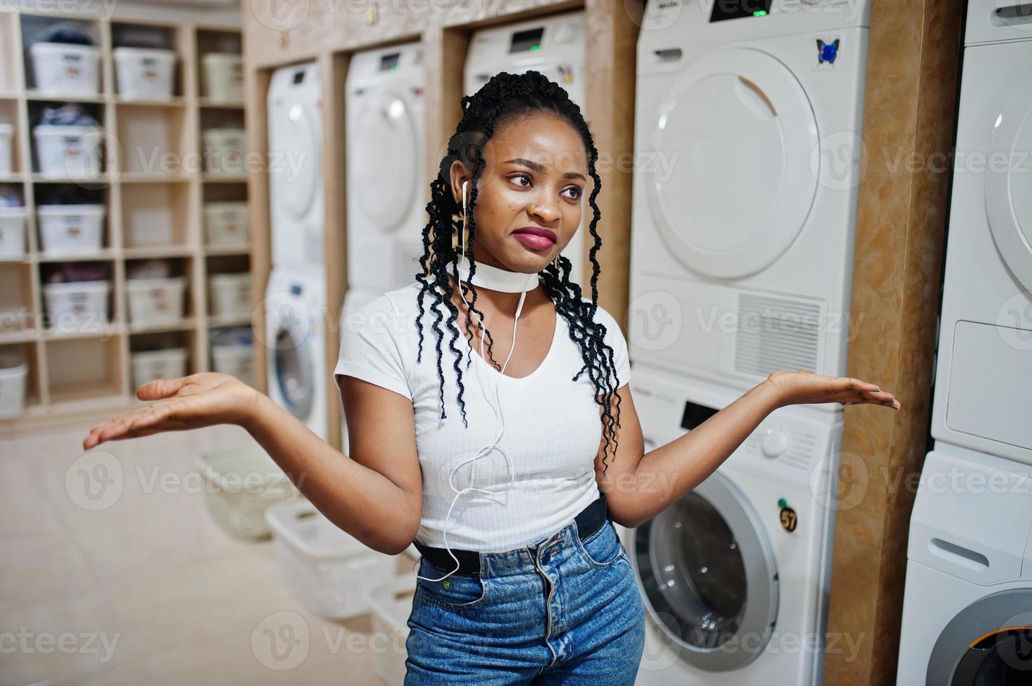 trieste en teleurgestelde Afro-Amerikaanse vrouw in de buurt van wasmachine in de zelfbedieningswasserette. foto