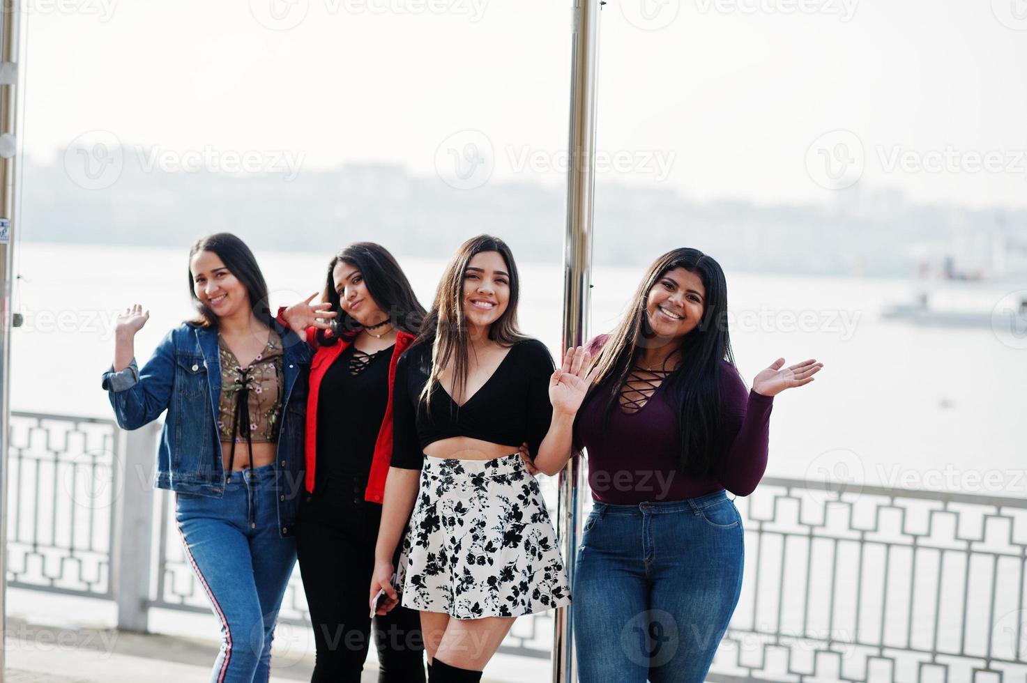 groep van vier gelukkige en mooie latino-meisjes uit ecuador poseerden tegen het meer met veerboot. foto