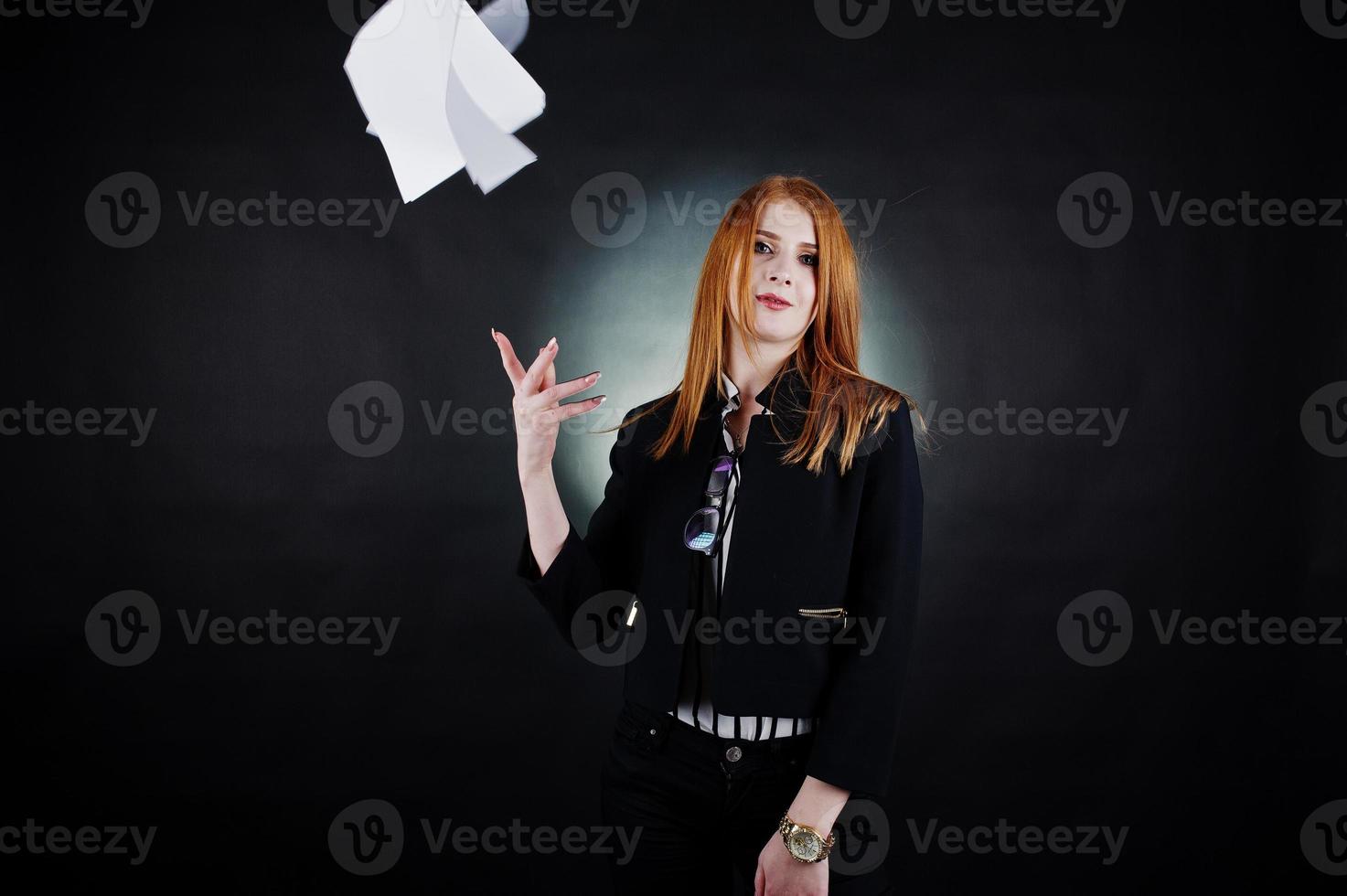 portret van een roodharige zakenvrouw in gestreepte blouse en jas die het papier weggooit. foto