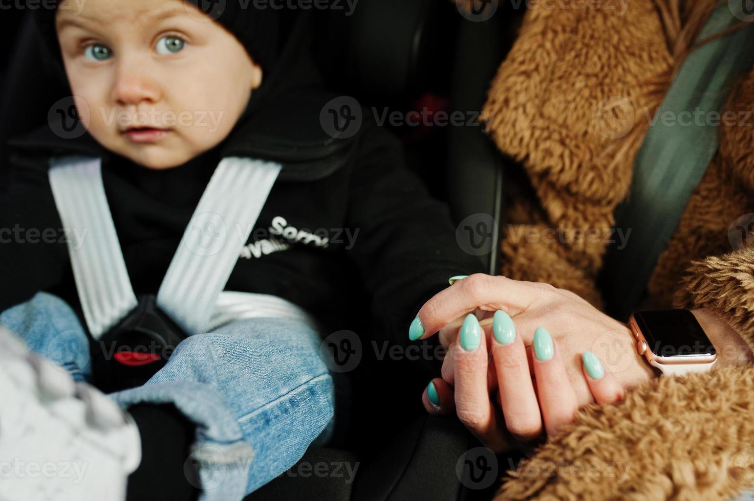 jonge moeder en kind in auto. kinderzitje op stoel. veiligheid rijden concept. foto