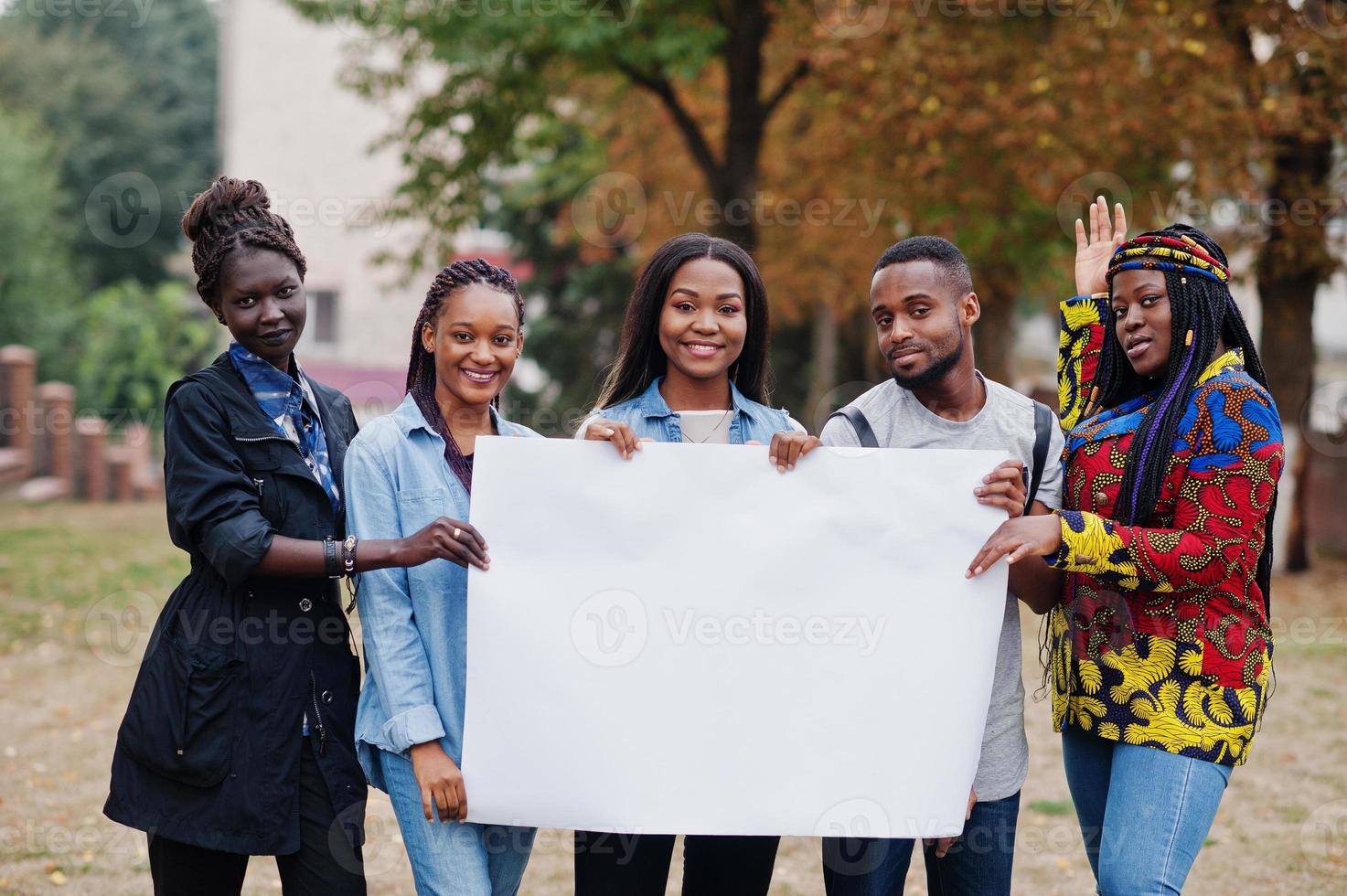 groep van vijf afrikaanse studenten op de campus van de universiteitswerf houdt een lege witte blanco vast. vrije ruimte voor uw tekst. zwarte afro-vrienden studeren. foto