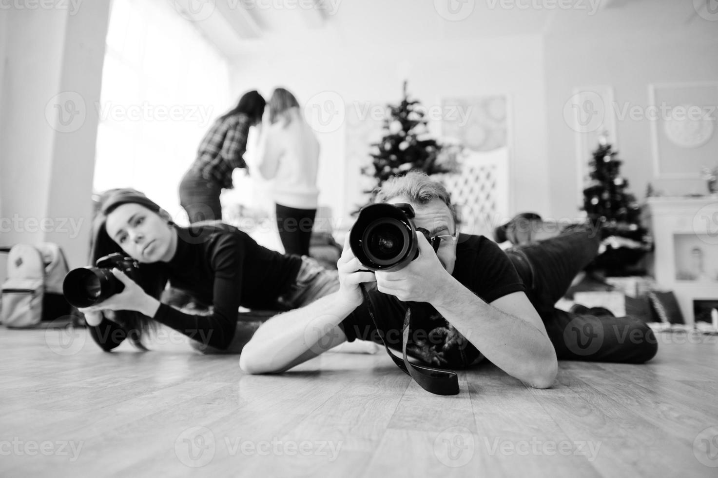 het team van twee fotografen ligt op de grond en fotografeert in de studio. foto