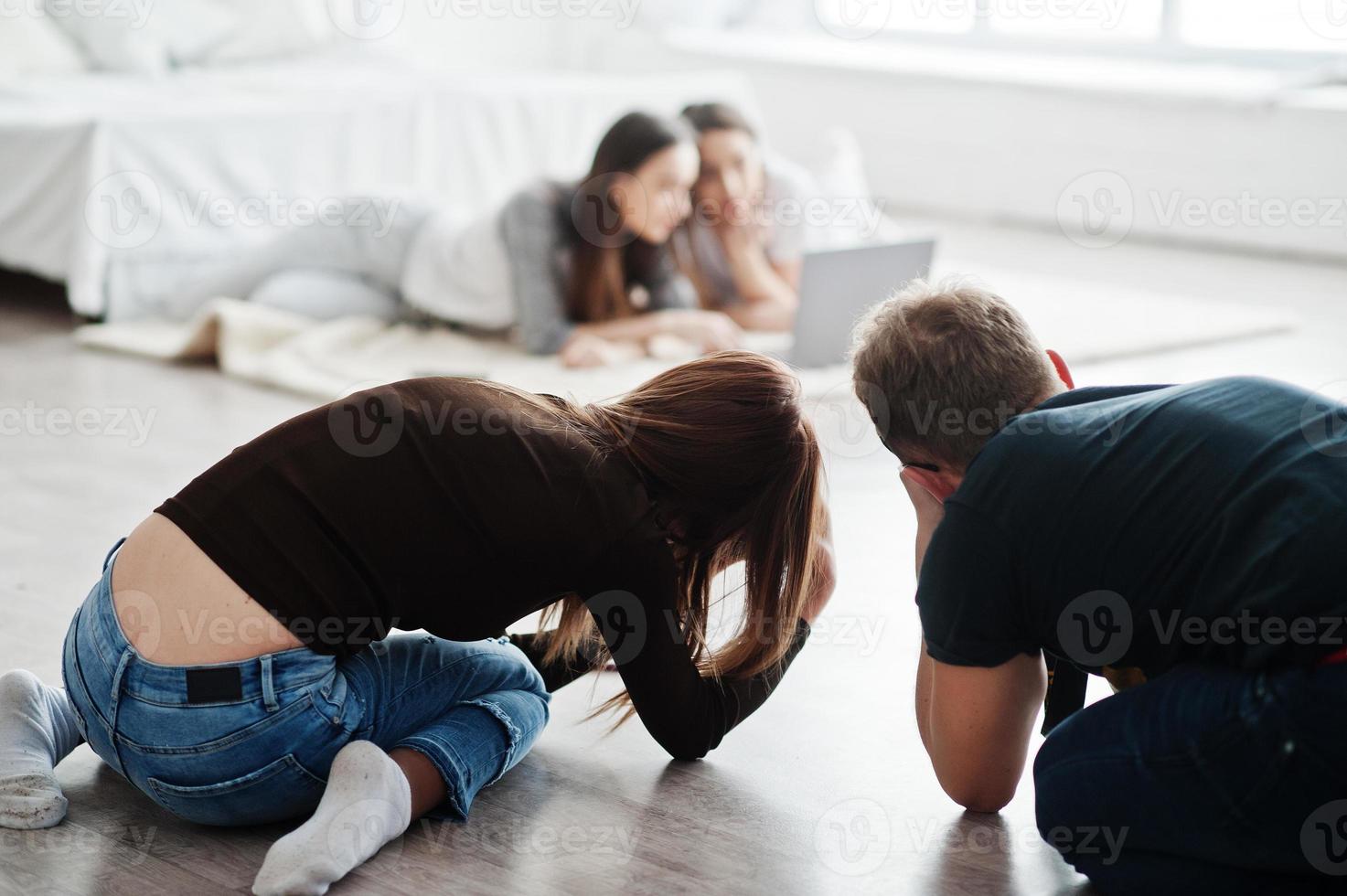 het team van twee fotografen die op studio op knieën schieten twee tweelingenmodellen die laptop bekijken. professionele fotograaf op het werk. masterclass. foto