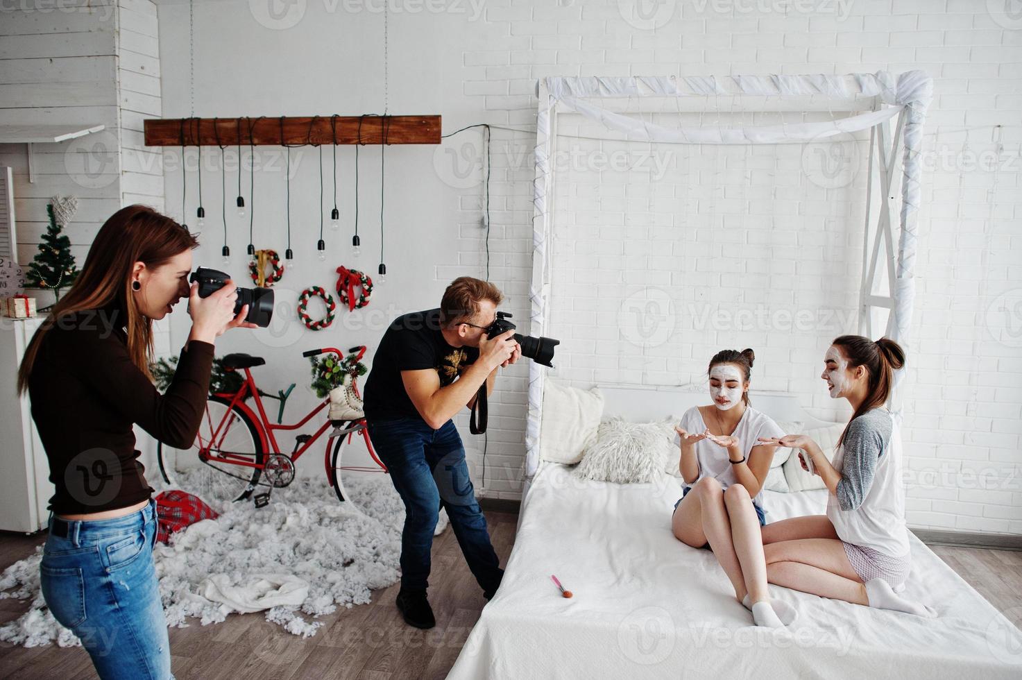 het team van twee fotografen die foto's maken van studio-tweelingmeisjes terwijl ze hun eigen maskercrème maken. professionele fotograaf op het werk. foto