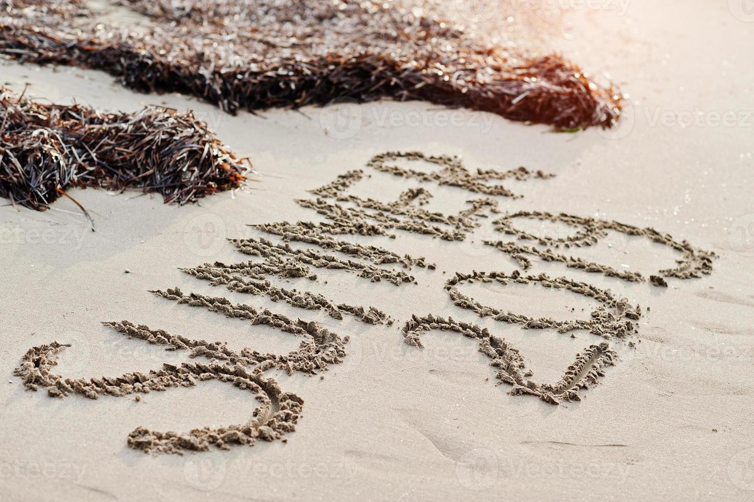 inscriptie zomer 2019 en algen op het zand op het strand. foto