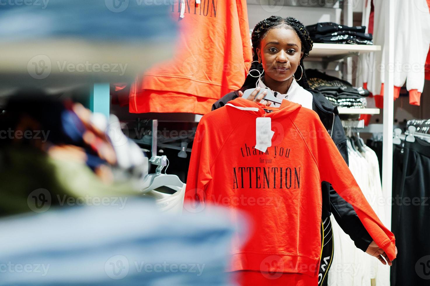 Afro-Amerikaanse vrouwen in trainingspakken winkelen bij sportkleding winkelcentrum tegen planken met sweatshirt. sport winkel thema. foto