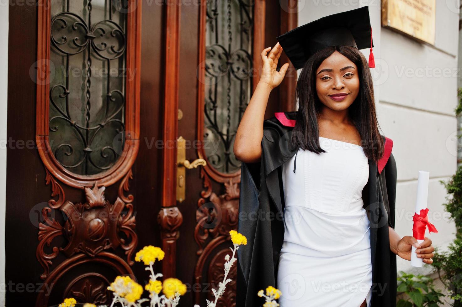 jonge vrouwelijke Afro-Amerikaanse student met diploma poseert buitenshuis. foto