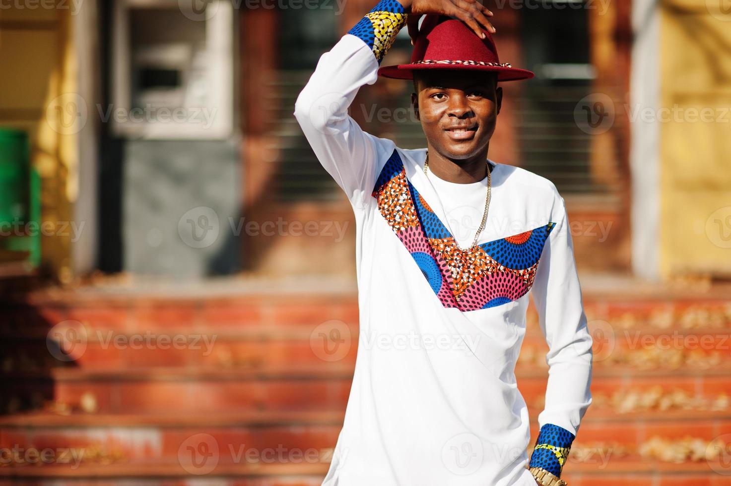 stijlvolle trendy afro frankrijk man in rode hoed en witte outfit poseerde op herfstdag. zwarte Afrikaanse modelman. foto