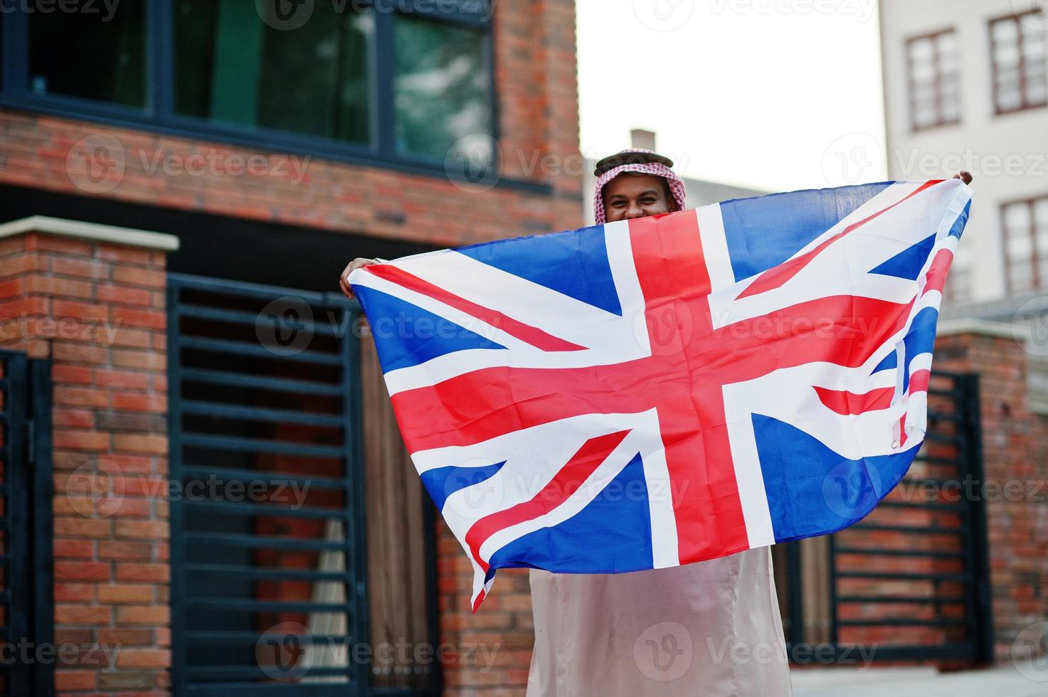 Arabische man uit het Midden-Oosten poseerde op straat met de vlag van Groot-Brittannië. engeland en arabische landen concept. foto