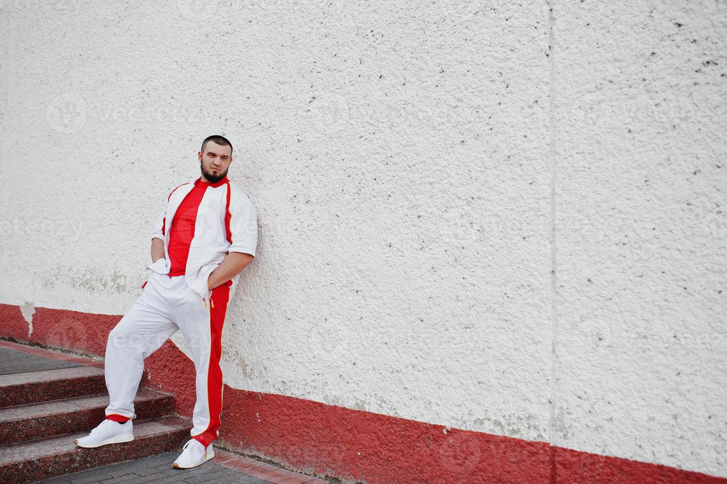 jonge brute bebaarde gespierde man draagt een wit sportpak met rood shirt. foto