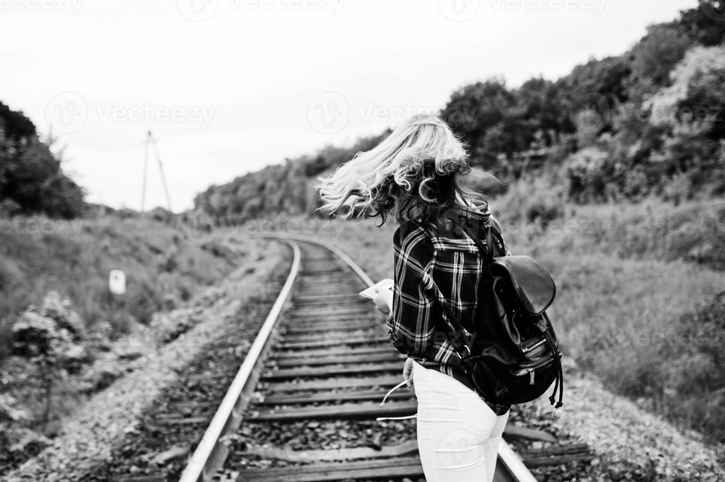 portret van een mooi blond meisje in tartan shirt wandelen op de spoorlijn met kaart in haar handen. foto