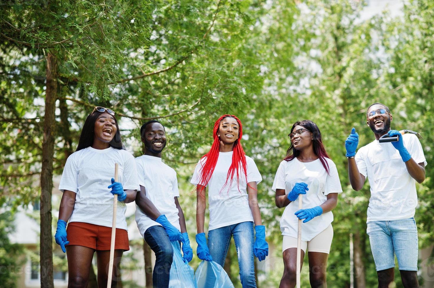 groep gelukkige afrikaanse vrijwilligers met vuilniszakken schoonmaakgebied in park. Afrika vrijwilligerswerk, liefdadigheid, mensen en ecologie concept. foto