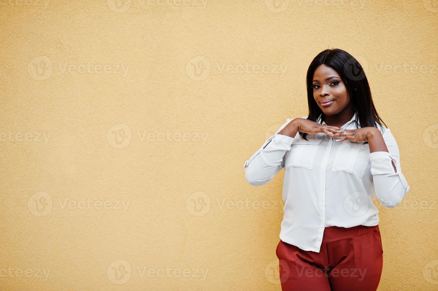 formeel geklede Afro-Amerikaanse zakenvrouw in witte blouse en rode broek geïsoleerd op gele achtergrond. succesvolle zakenvrouw met een donkere huid. foto