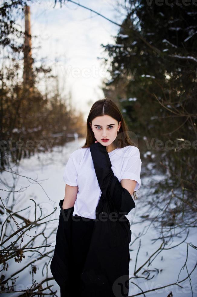 modieuze lange benen brunette model in lange zwarte mantel poseerde buiten op winterdag. foto