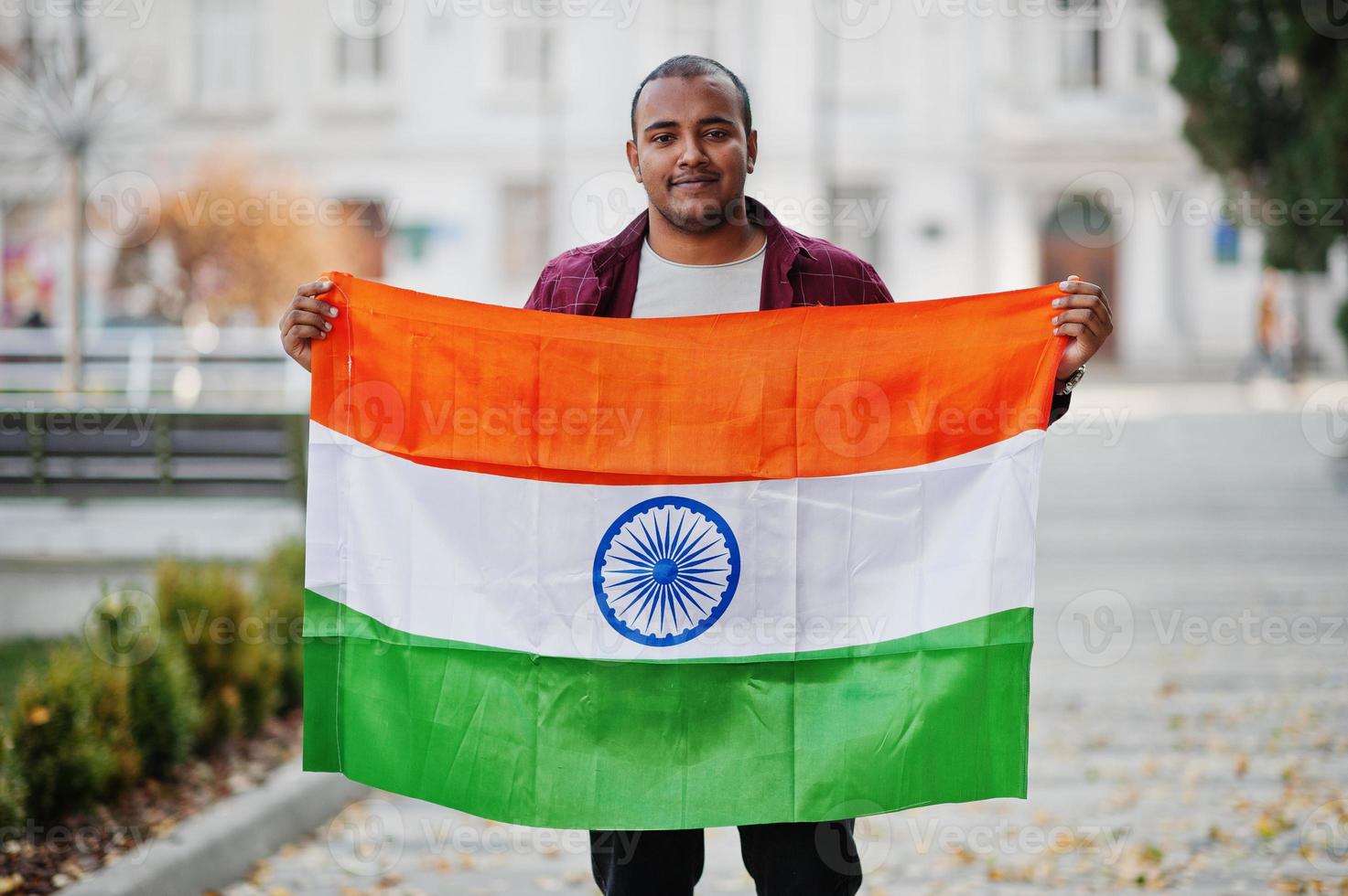 Zuid-Aziatische Indiase mannelijke student met de vlag van india buiten geposeerd. foto