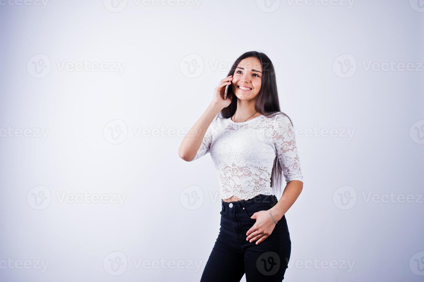 portret van een jonge mooie vrouw in witte top en zwarte broek met behulp van haar telefoon. foto