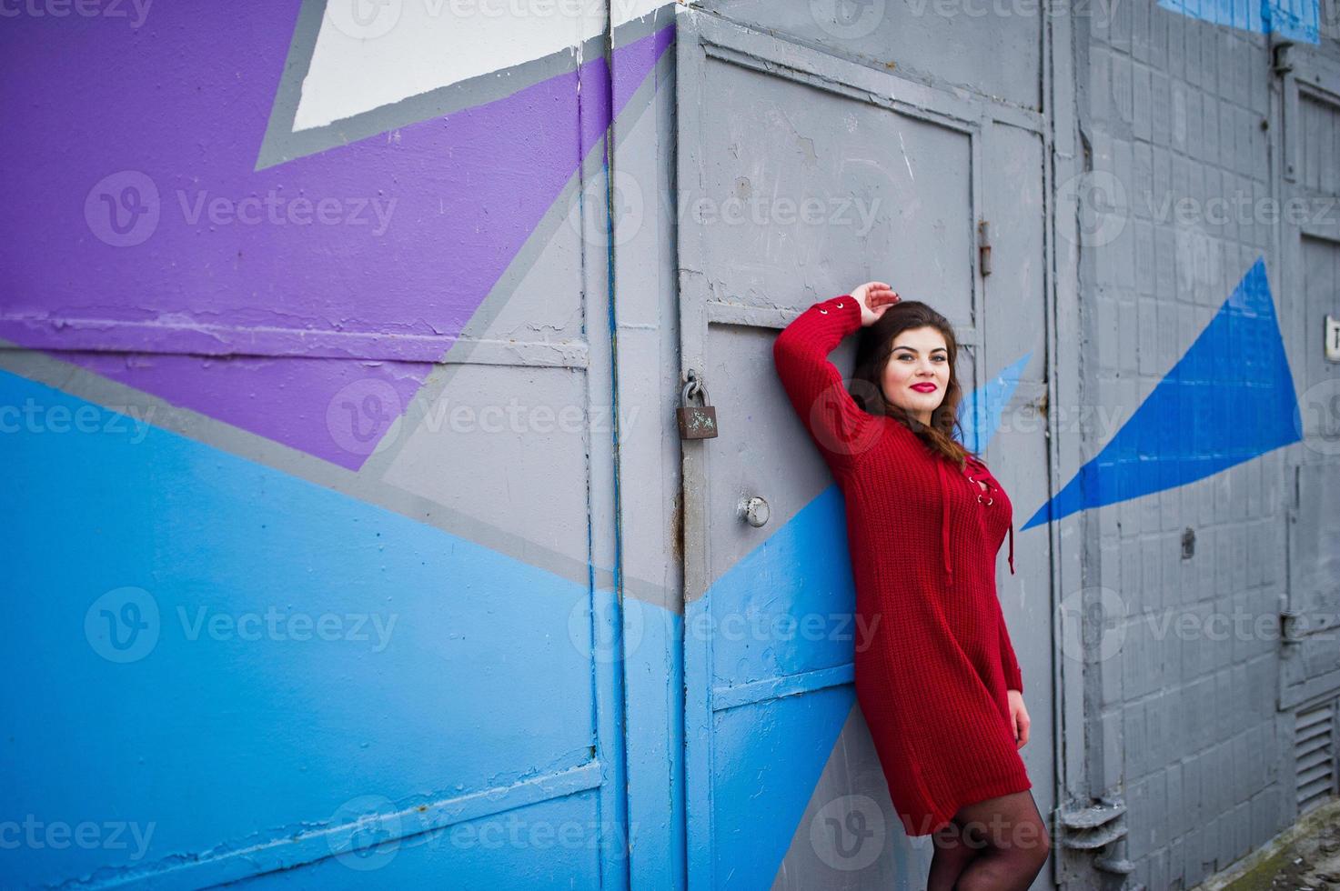 brunette plus size model op rood tegen gekleurde muur. foto