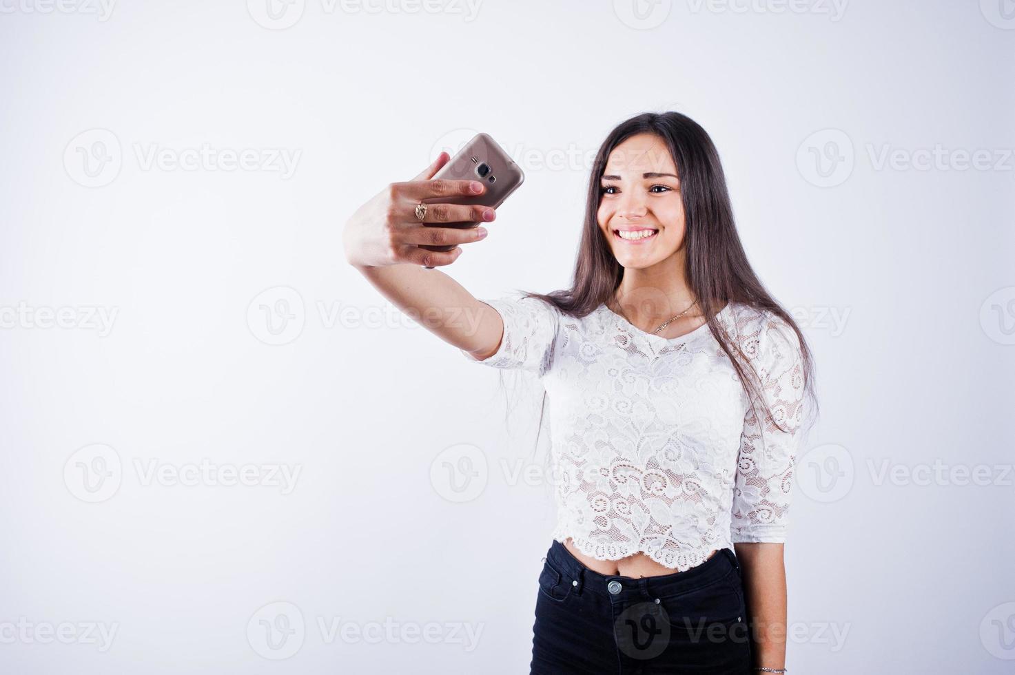 portret van een jonge mooie vrouw in witte top en zwarte broek die selfie neemt. foto