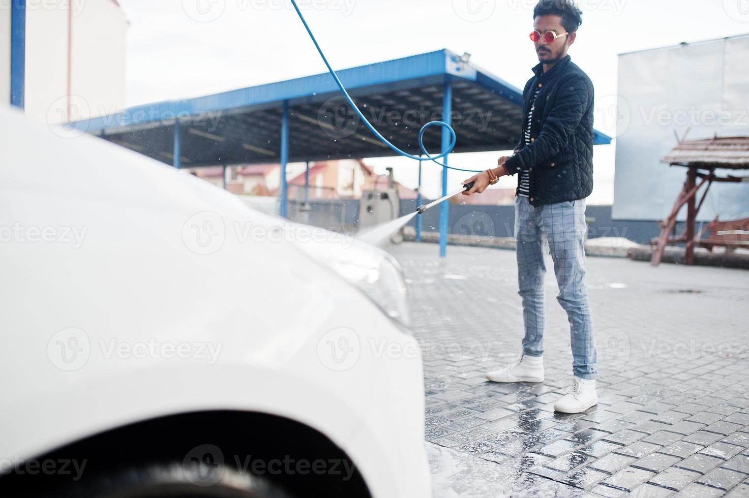 Zuid-Aziatische man of Indiase man die zijn witte transport op autowasserette wast. foto