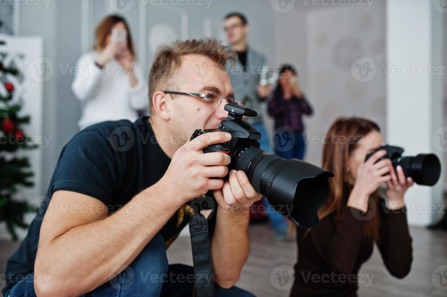 het team van twee fotografen die op studio achter nog eens drie arbeiders schieten. professionele fotograaf op het werk. masterclass. foto