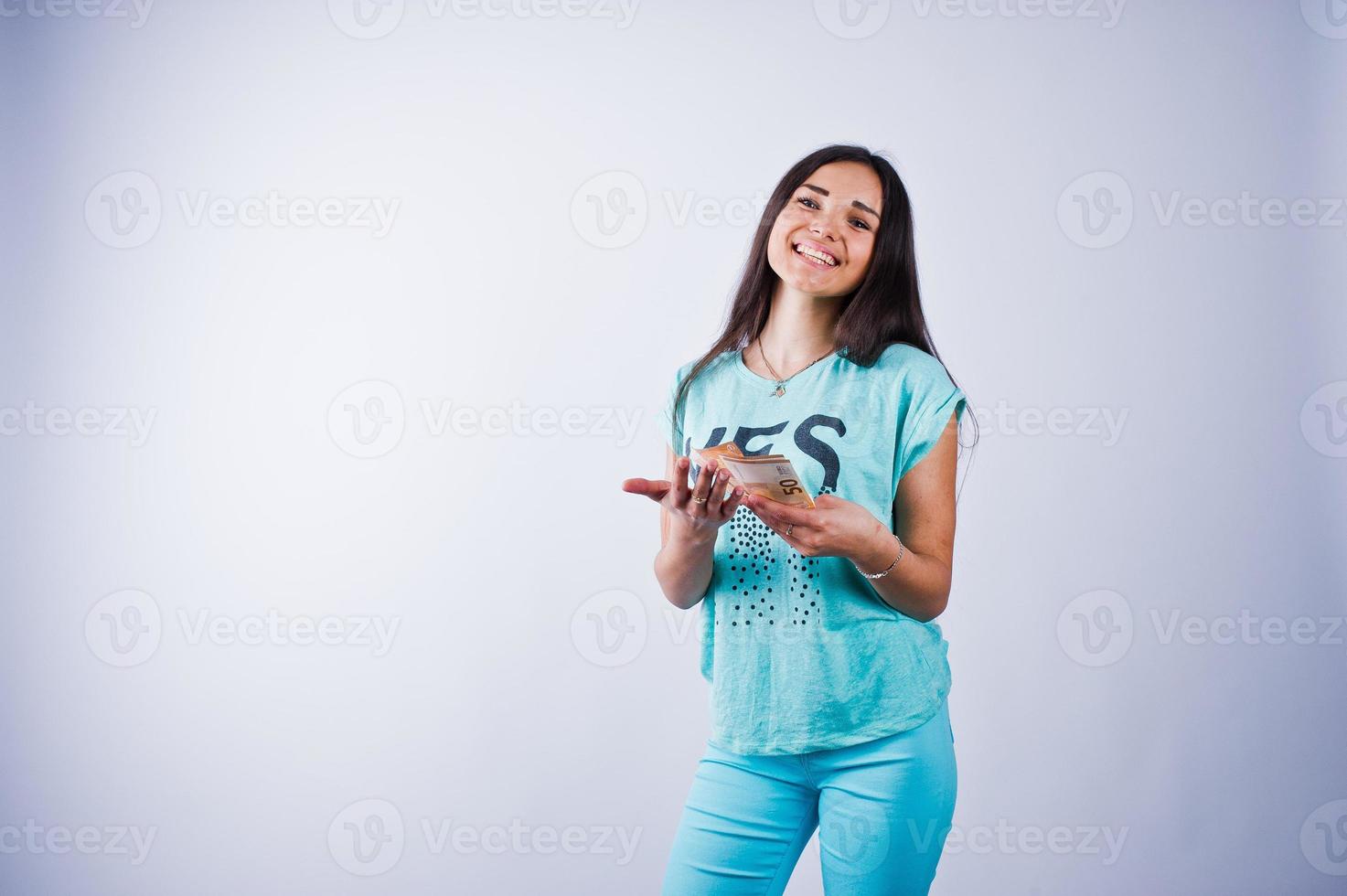 portret van een aantrekkelijk meisje in blauw of turquoise t-shirt en broek poseren met veel geld in haar hand. foto