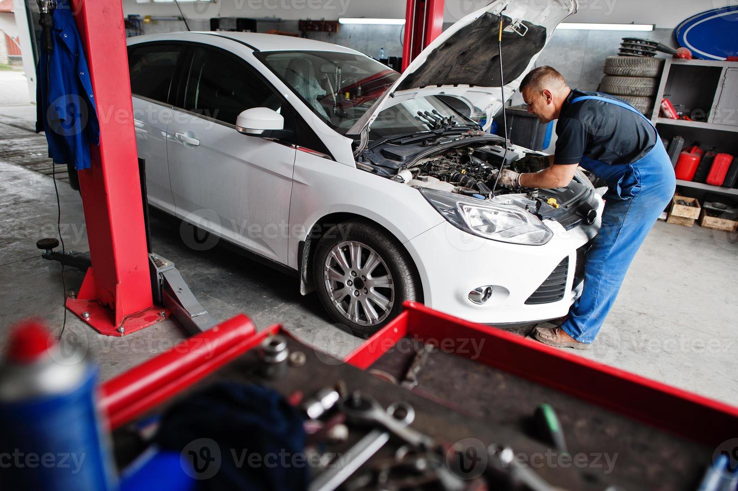 auto reparatie en onderhoud thema. monteur in uniform werken in autoservice, motor controleren. foto