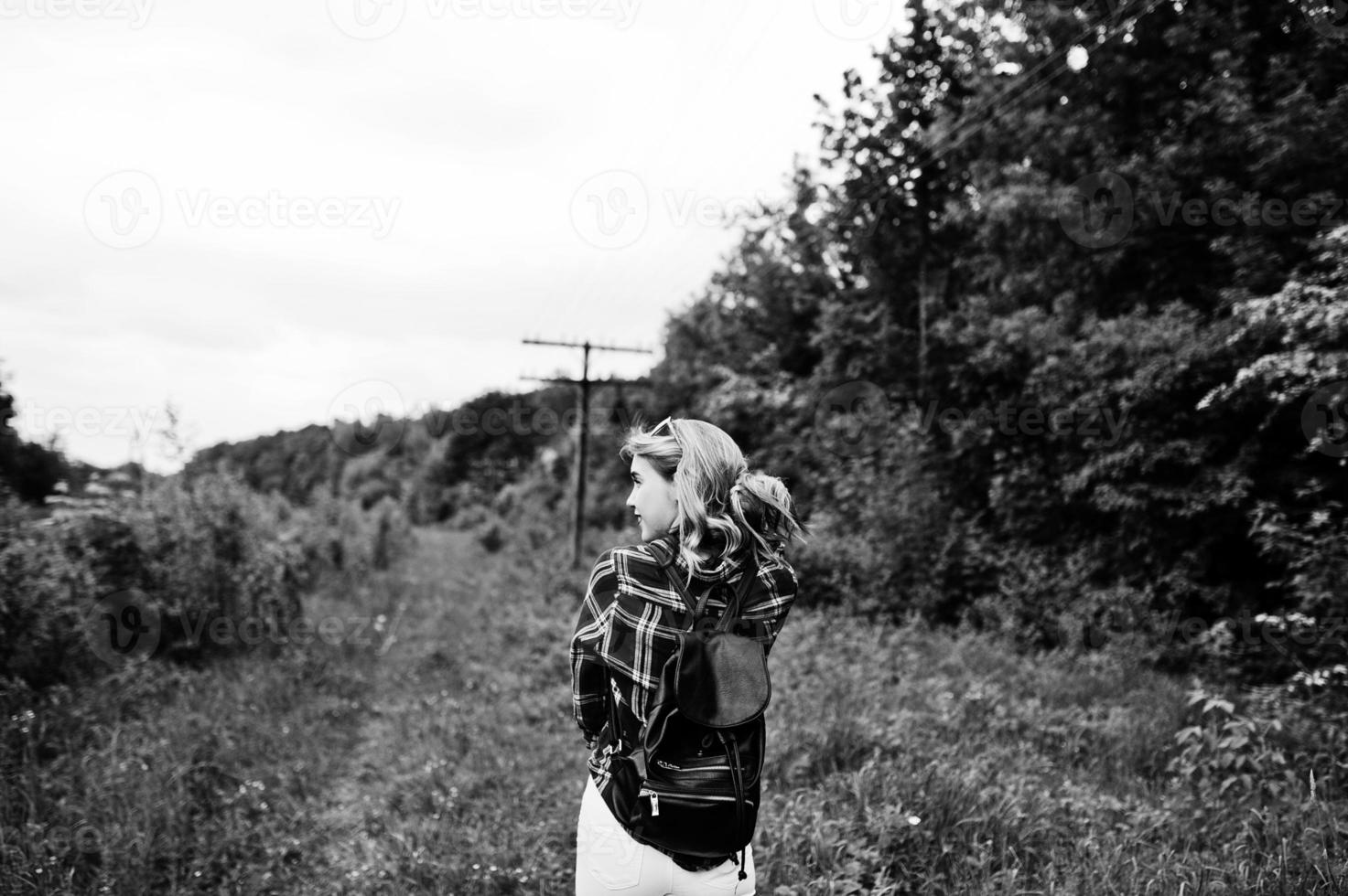 portret van een aantrekkelijk blond meisje in tartan shirt met rugzak wandelen op het platteland. foto