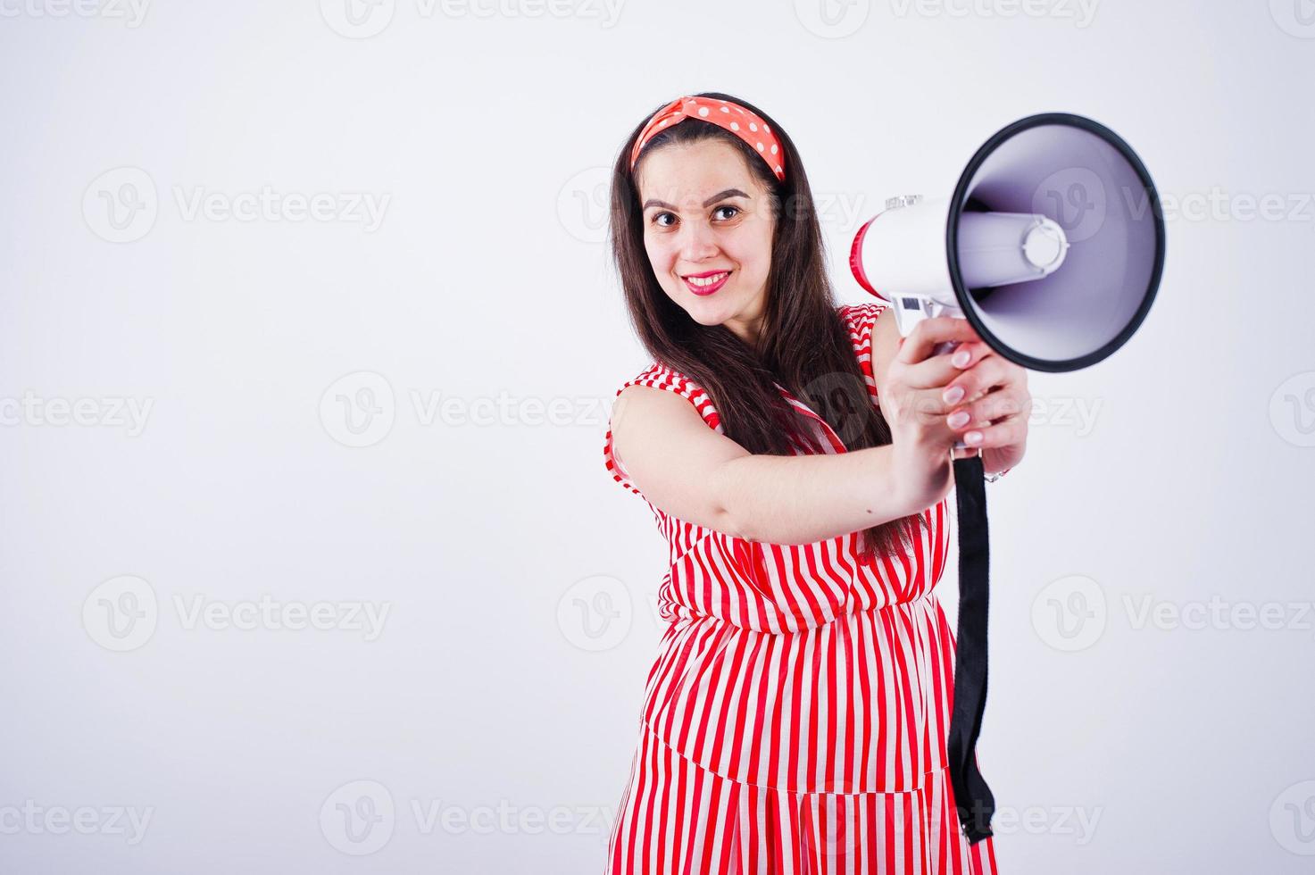 portret van een jonge mooie vrouw in rode jurk praten in megafoon. foto