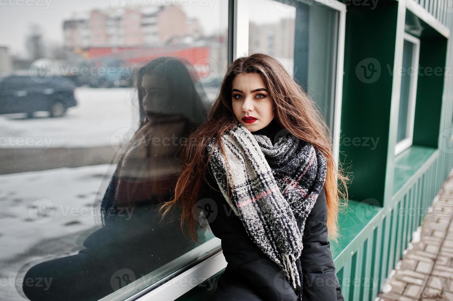 brunette stijlvolle casual meisje in sjaal tegen groene metalen muur. foto