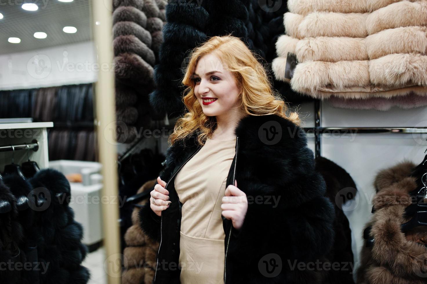 elegantie blond meisje in bontjas in de winkel van bontjassen en leren jassen. foto
