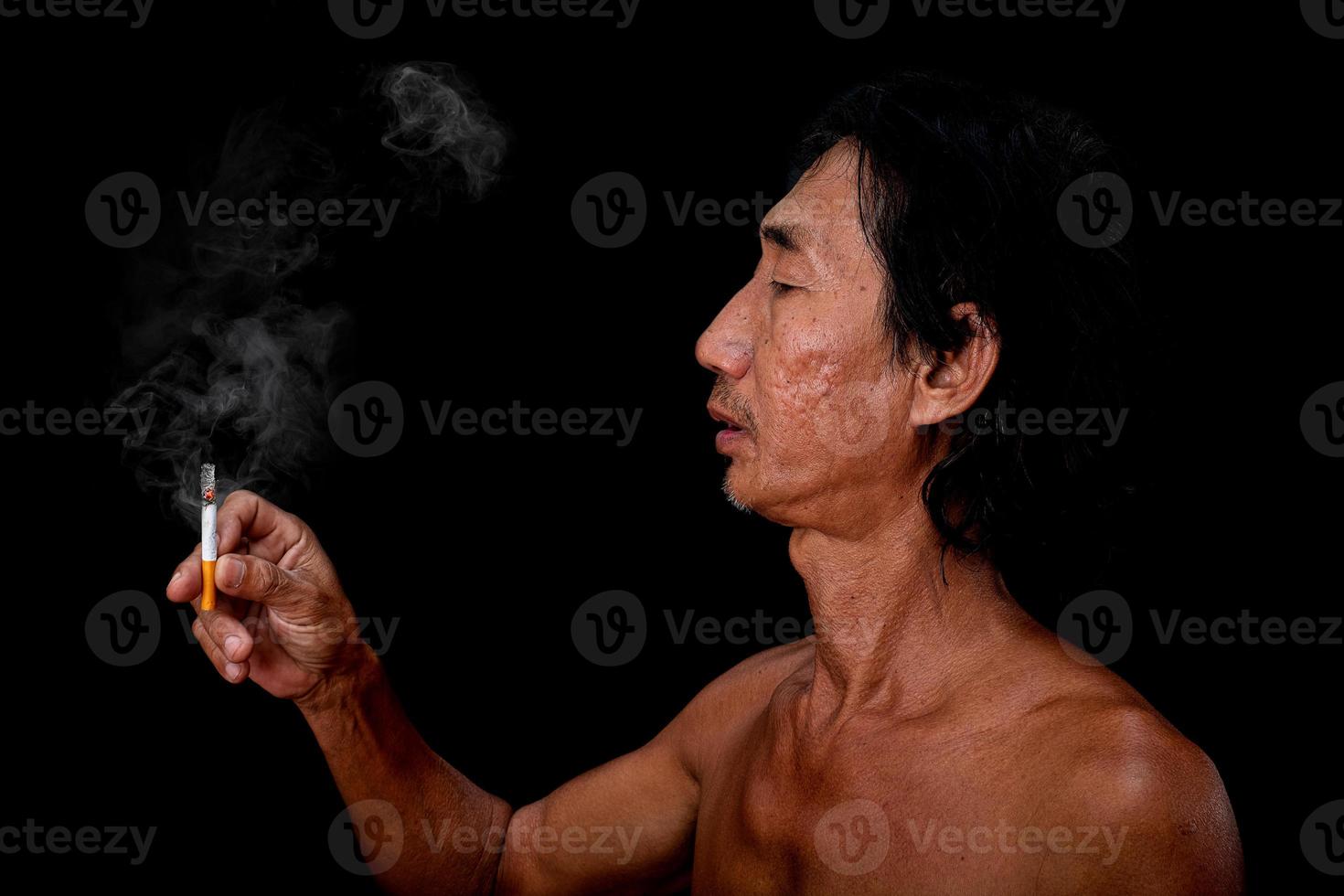 het portret slanke oude man rookte op de zwarte achtergrond, afbeelding van mannen hand met sigarettenrook verspreid in de mond concept foto