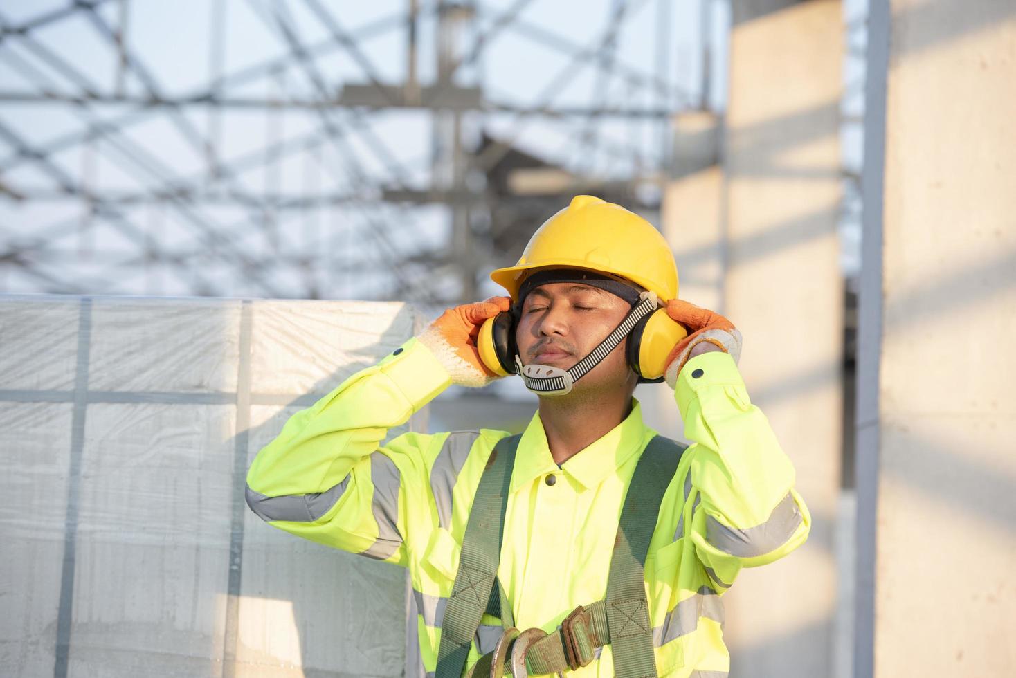 Aziatische ingenieurs in veiligheidshelmen en veiligheidsvesten voor werknemers met beschermende koptelefoons op bouwplaatsen. foto