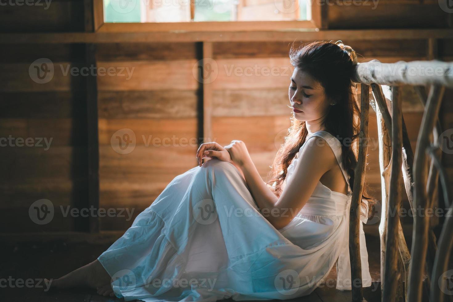 trieste aziatische vrouw die een witte jurk draagt die lijdt aan depressie slapeloosheid wakker en zit alleen op het bed in vintage slaapkamer. seksuele intimidatie en geweld tegen vrouwen. foto