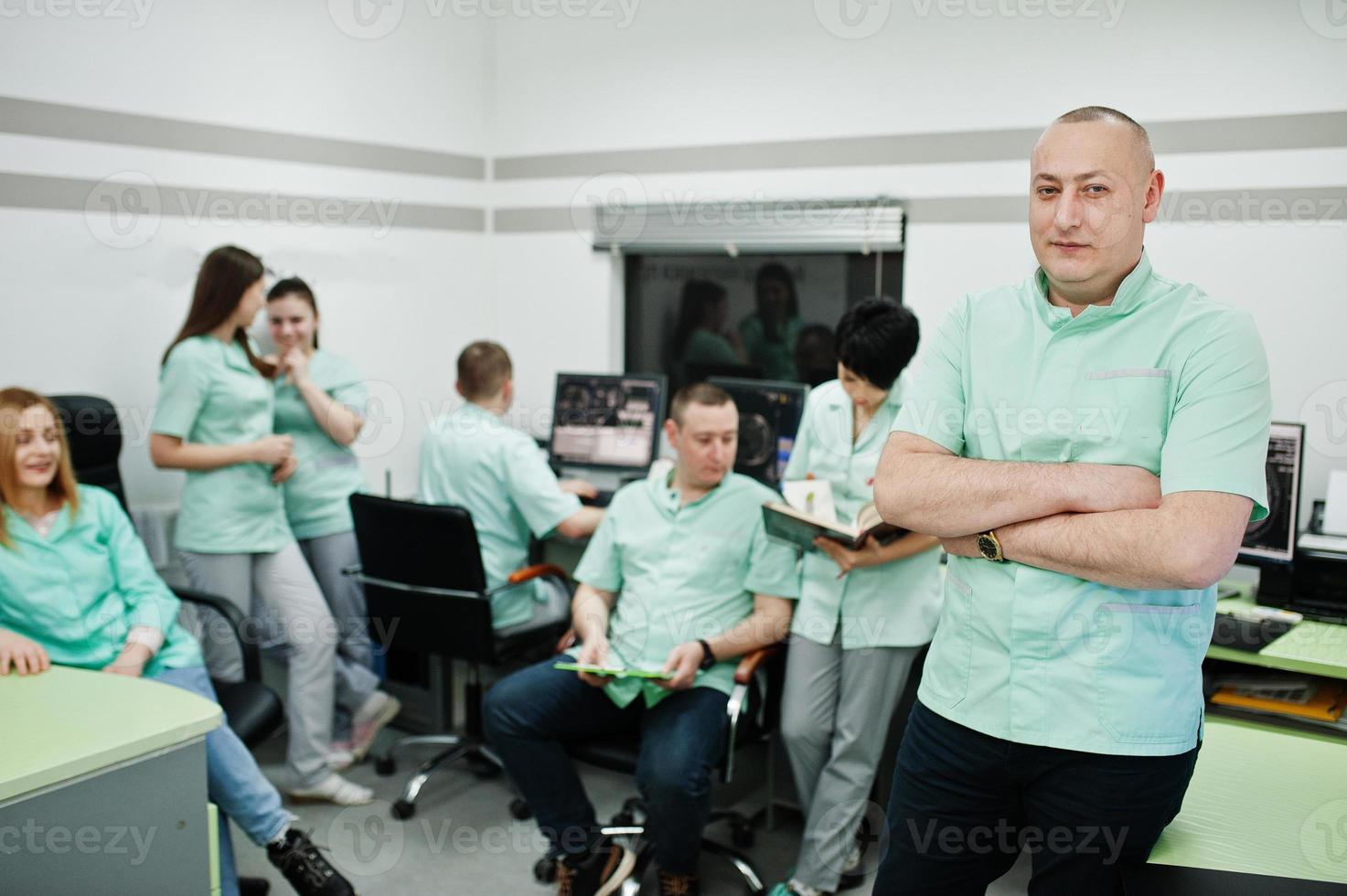 medisch thema .portrait van arts met klembord tegen groep artsen die bijeenkomen in het mri-kantoor in diagnostisch centrum in het ziekenhuis. foto